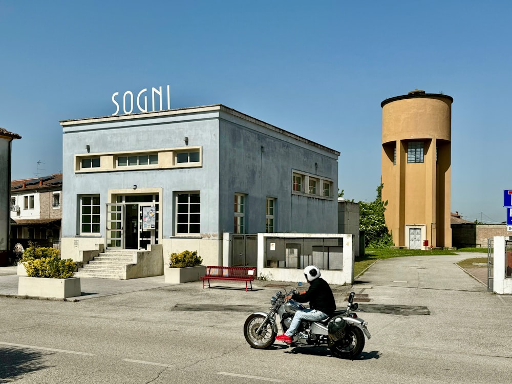 a person riding a motorcycle in front of a building