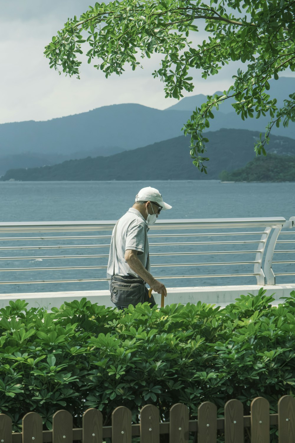 a man in a white hat is walking by the water
