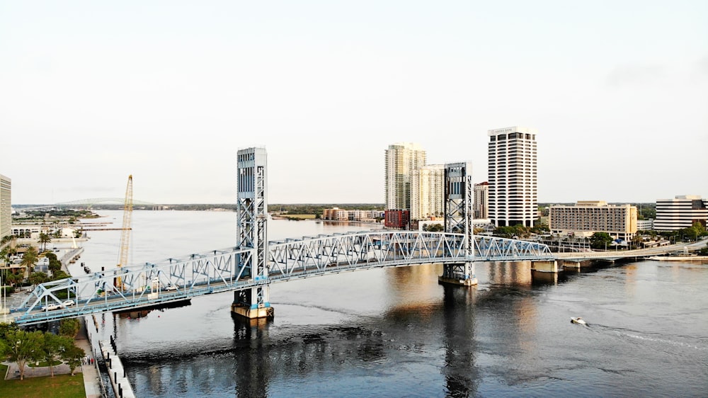 a bridge spanning over a river with a city in the background
