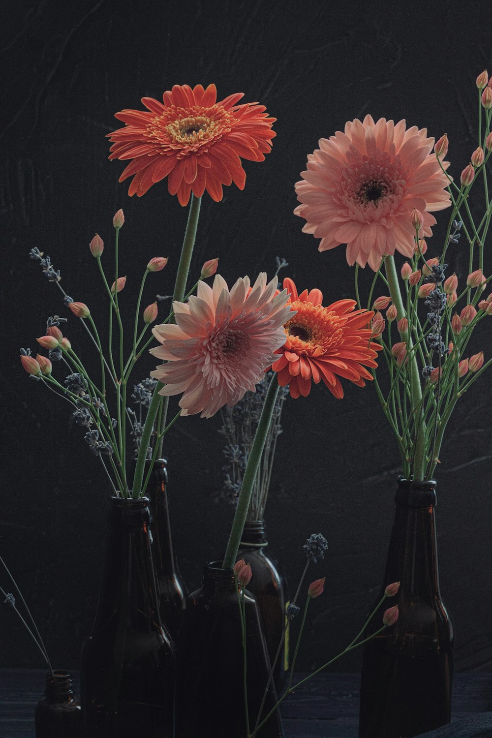 a group of three vases with flowers in them