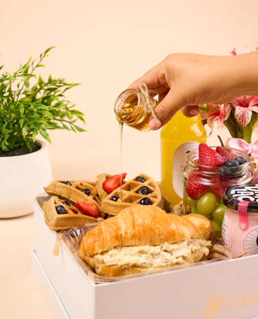 a person is pouring honey into a box of food