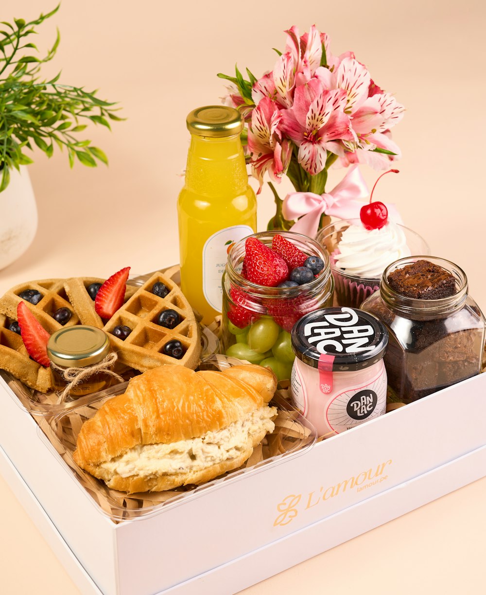 a white box filled with food and a vase of flowers