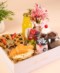 a white box filled with food and a vase of flowers