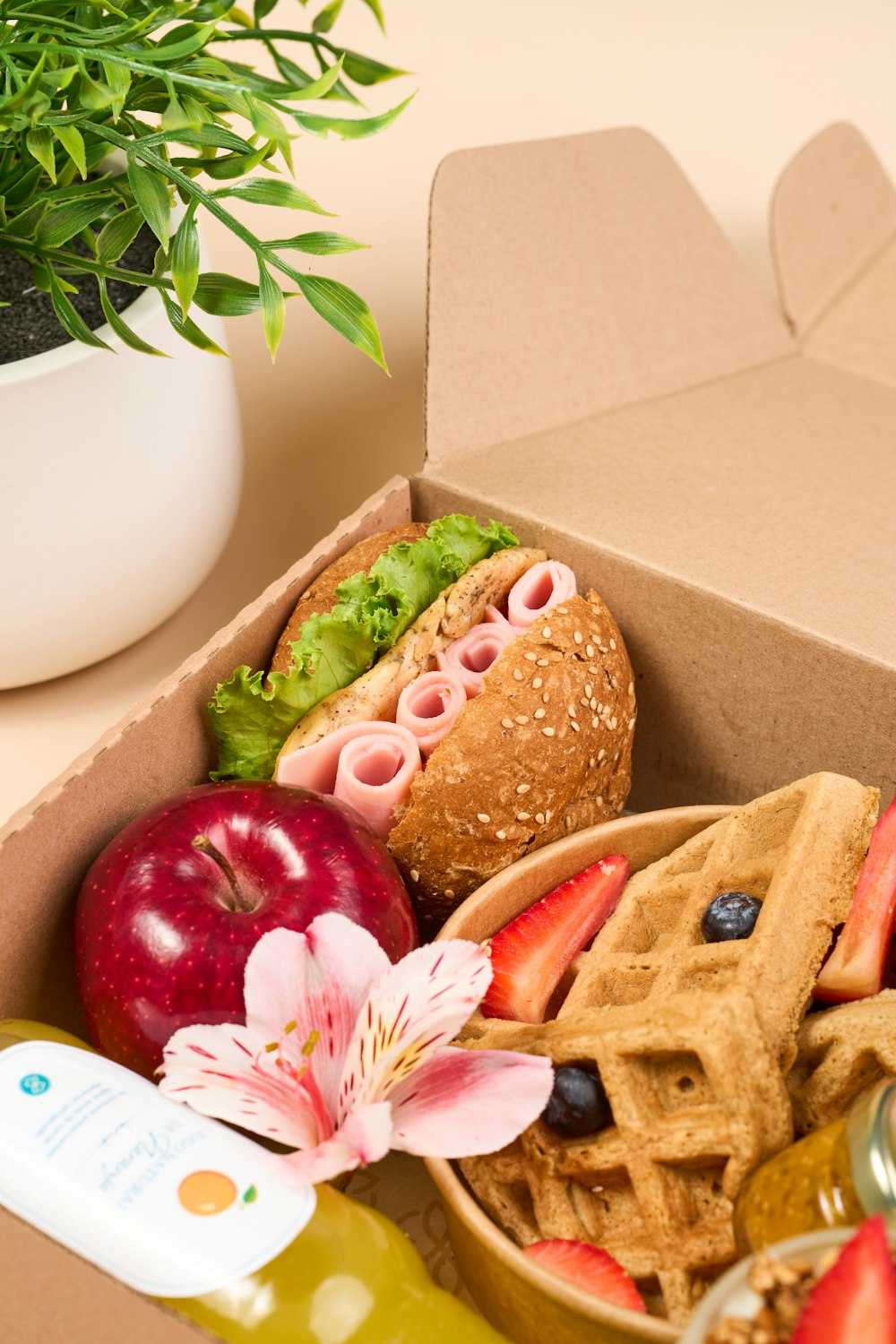 a box filled with a sandwich, waffles and fruit