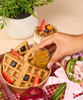 a person putting a jar of jam on top of a waffle