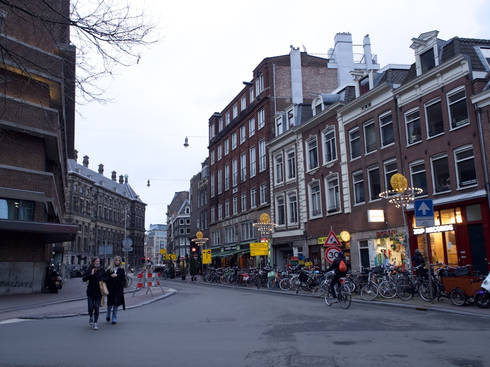 a group of people walking down a street next to tall buildings