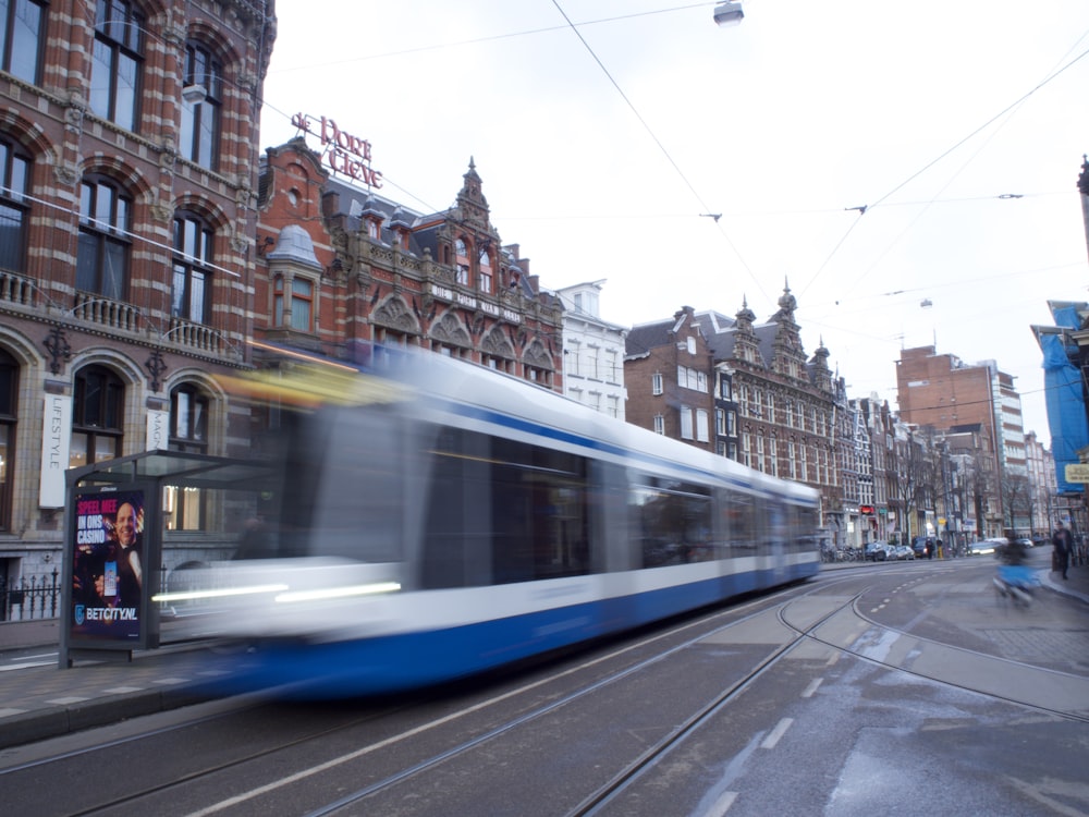 a blue and white train traveling past a tall building