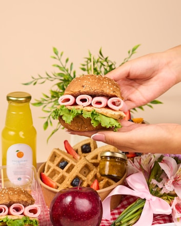 a person holding a sandwich in front of a plate of food