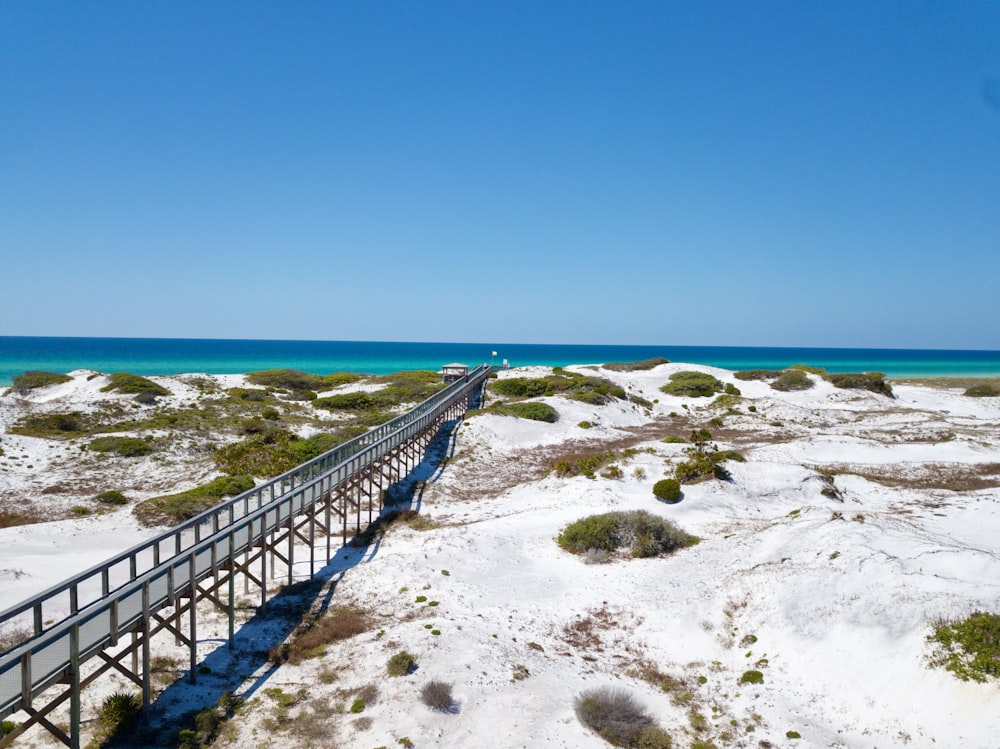 a wooden bridge over a sandy beach next to the ocean