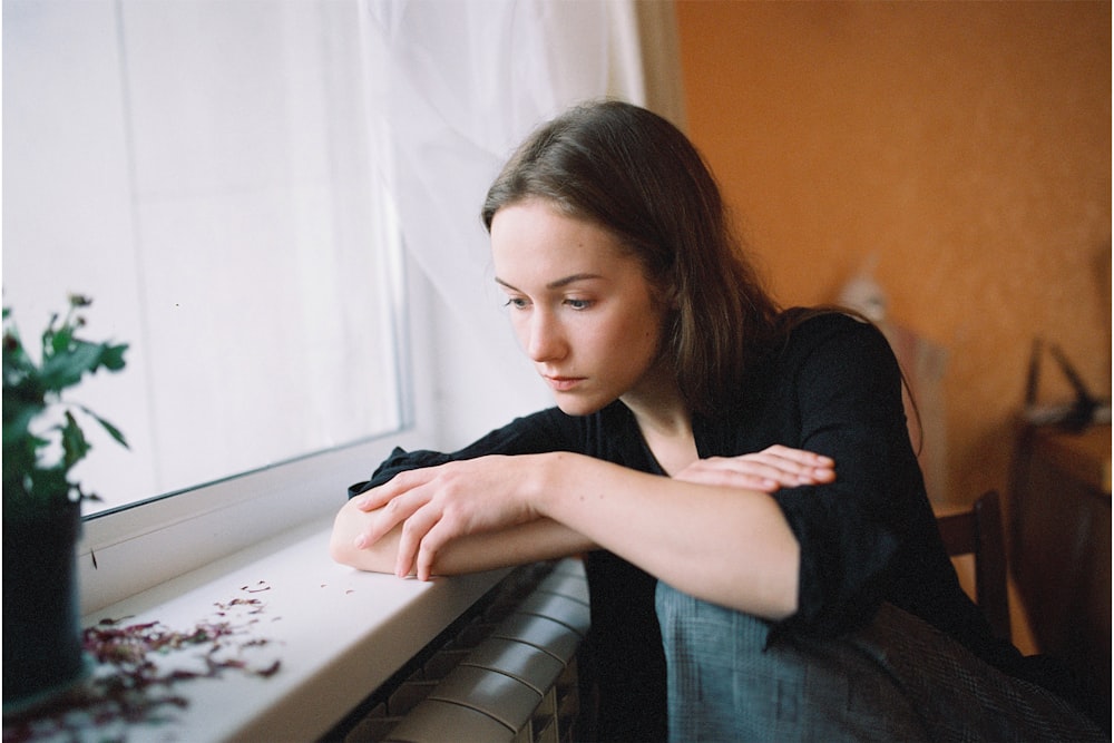 a woman sitting on a window sill looking out the window