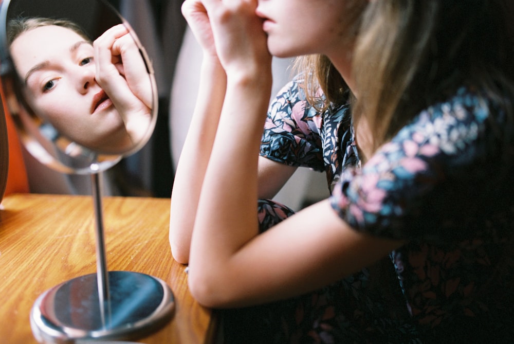 a girl looking at her reflection in a mirror