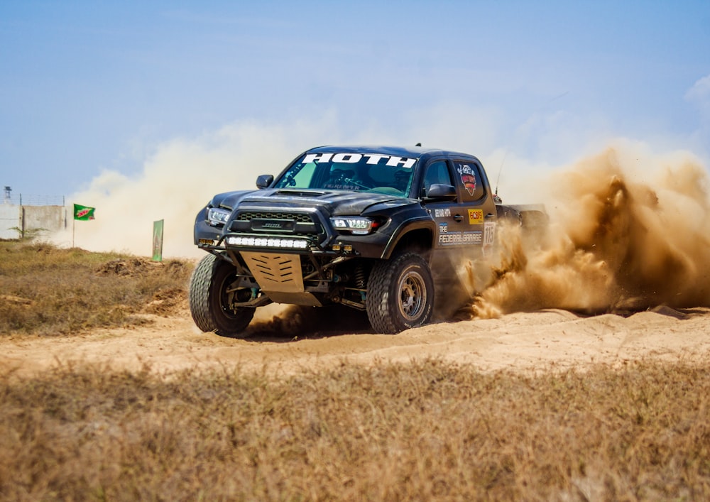 a black truck driving down a dirt road