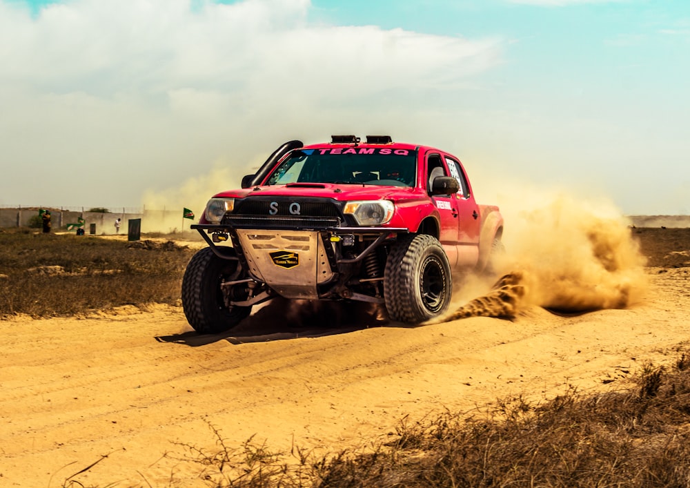 a red truck driving down a dirt road