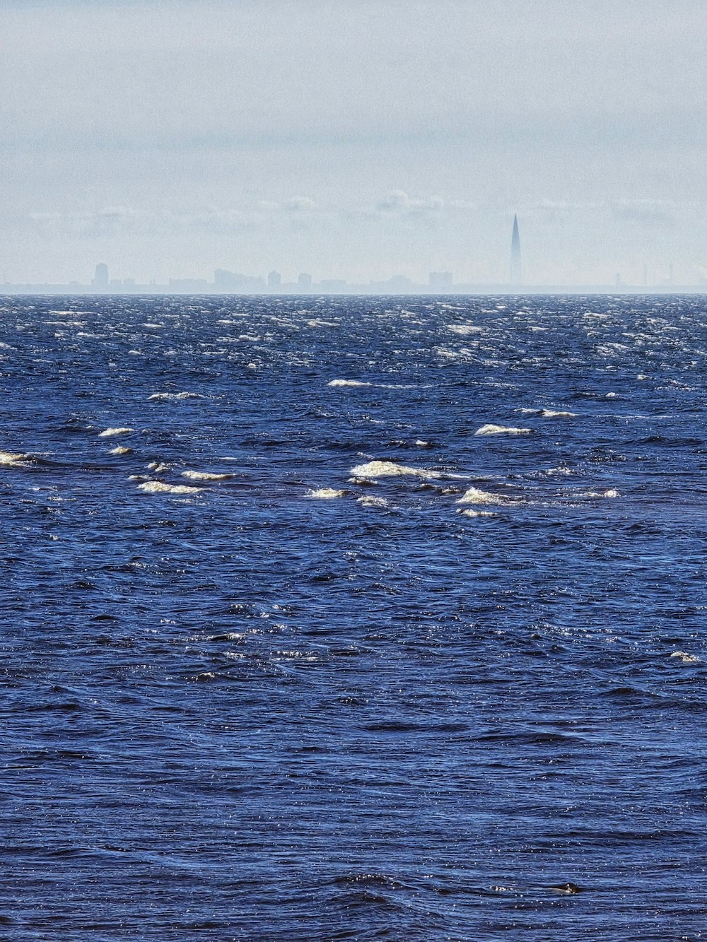 a large body of water with a lighthouse in the distance