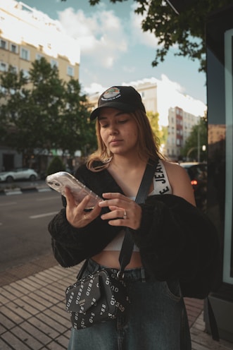 a woman standing on a sidewalk looking at her cell phone