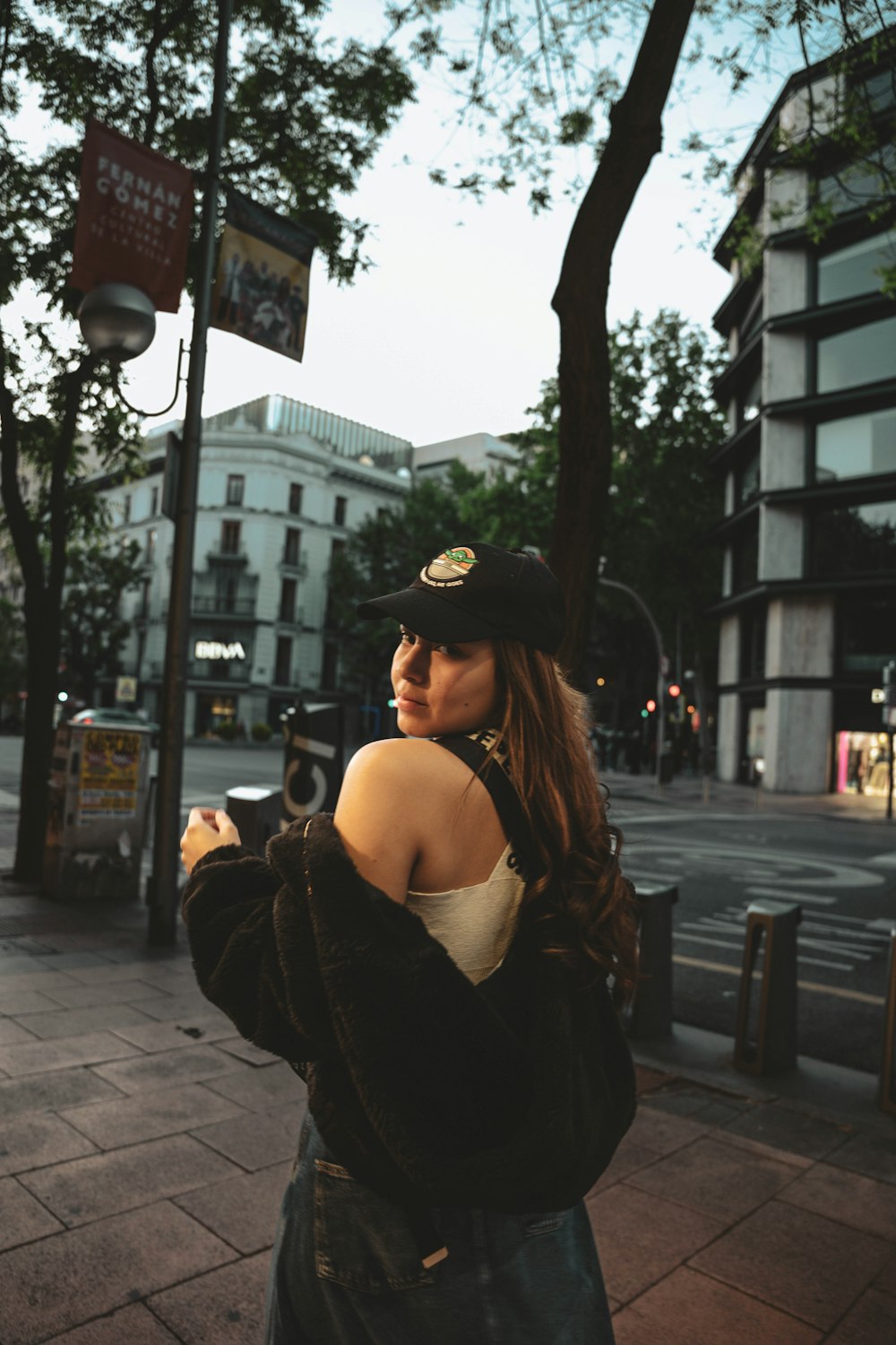 a woman standing on a sidewalk looking at her cell phone