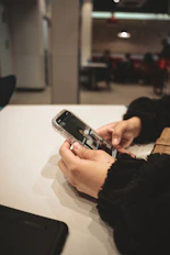 a person holding a cell phone on a table