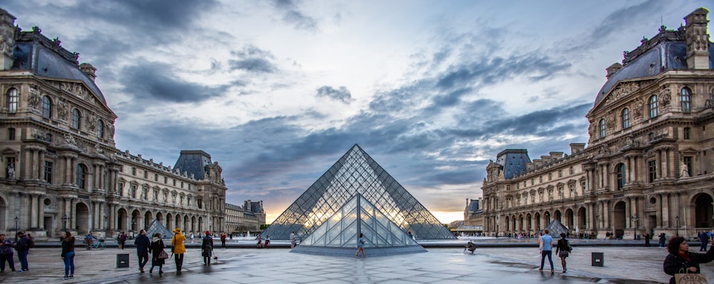 a group of people standing around a glass pyramid