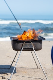 a grill on the beach with a fishing rod sticking out of it