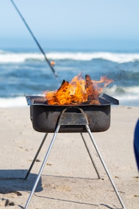 a grill on the beach with a fishing rod sticking out of it
