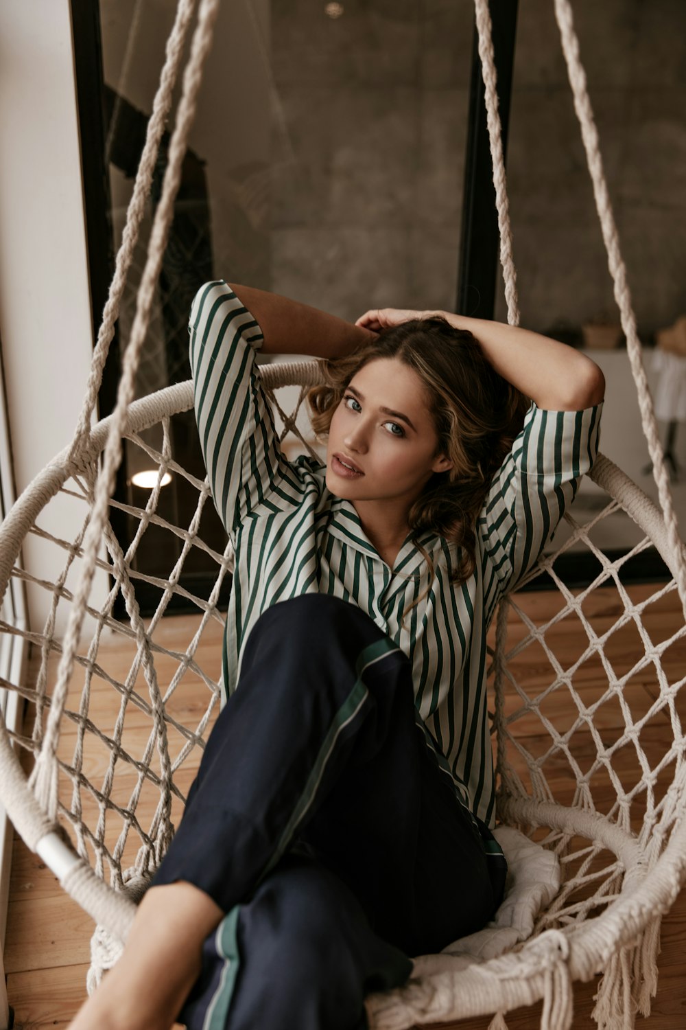 a woman sitting in a hammock with her hands on her head