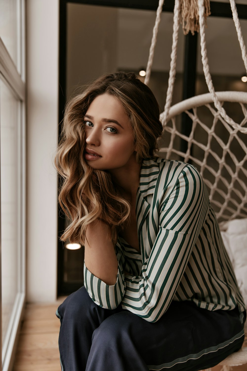 a woman sitting on the floor next to a hammock