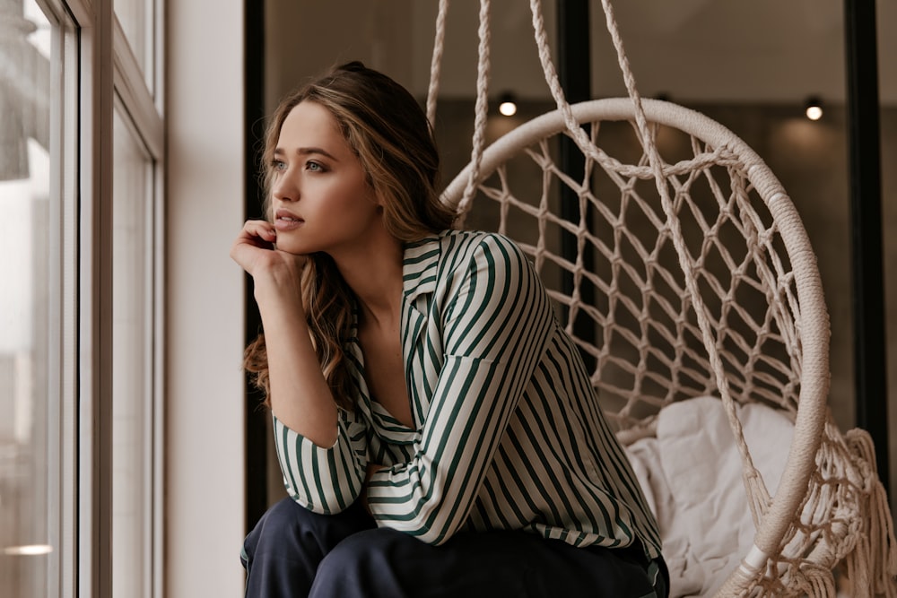 a woman sitting in a chair next to a window