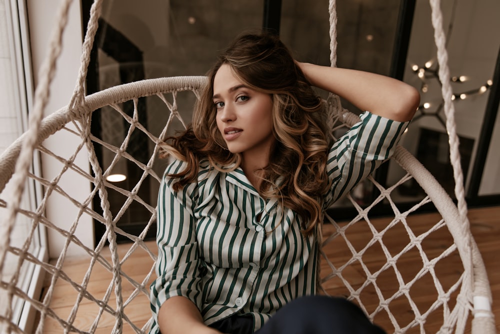 a woman sitting in a hammock with her hands on her head