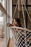 a woman sitting in a hammock looking out a window