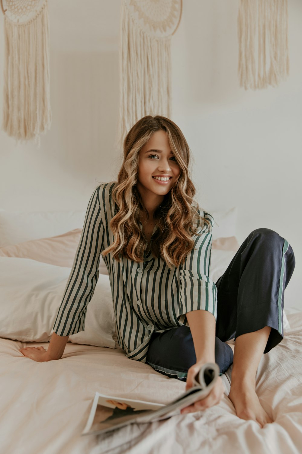 a woman sitting on a bed with a magazine