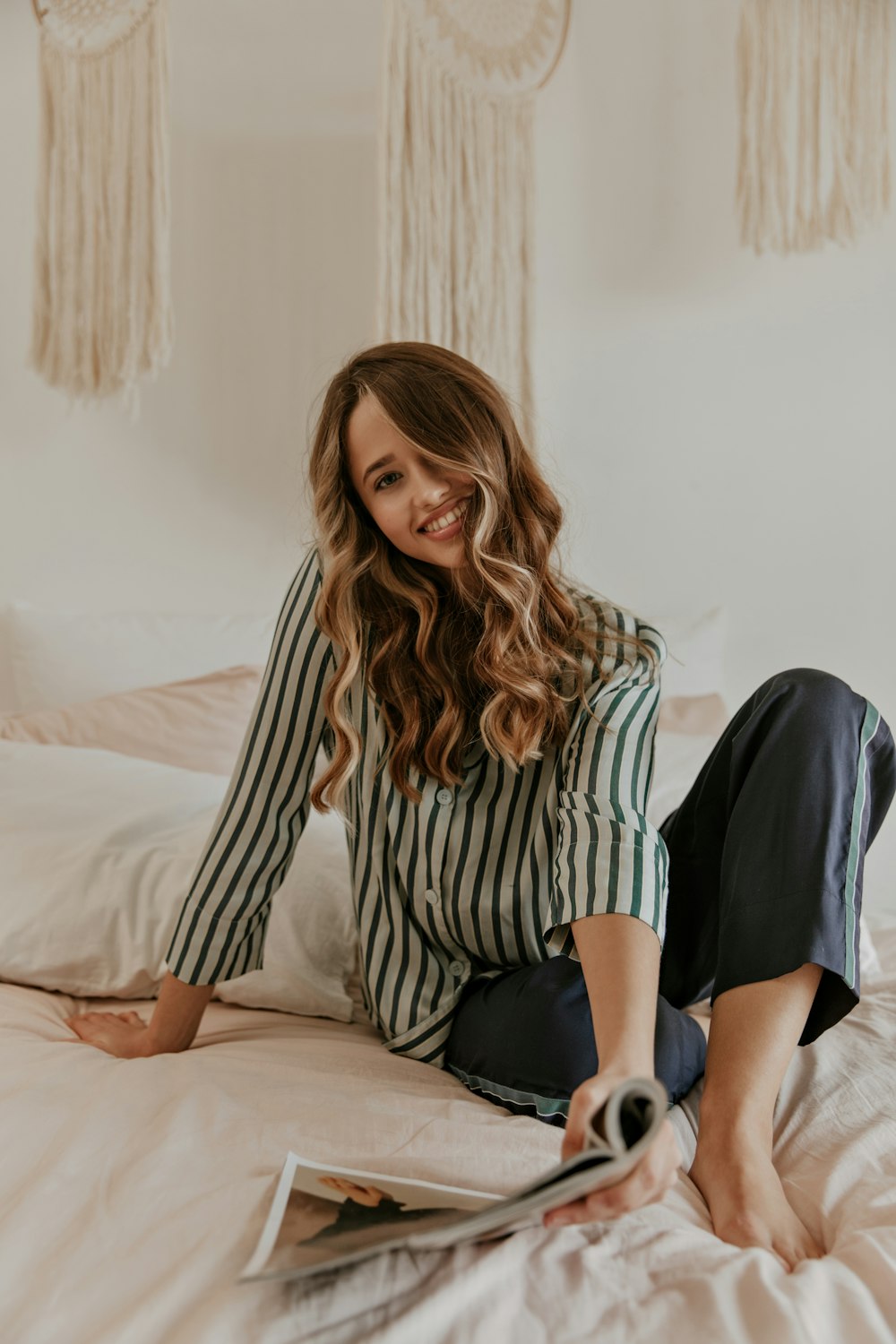 a woman sitting on a bed with a magazine