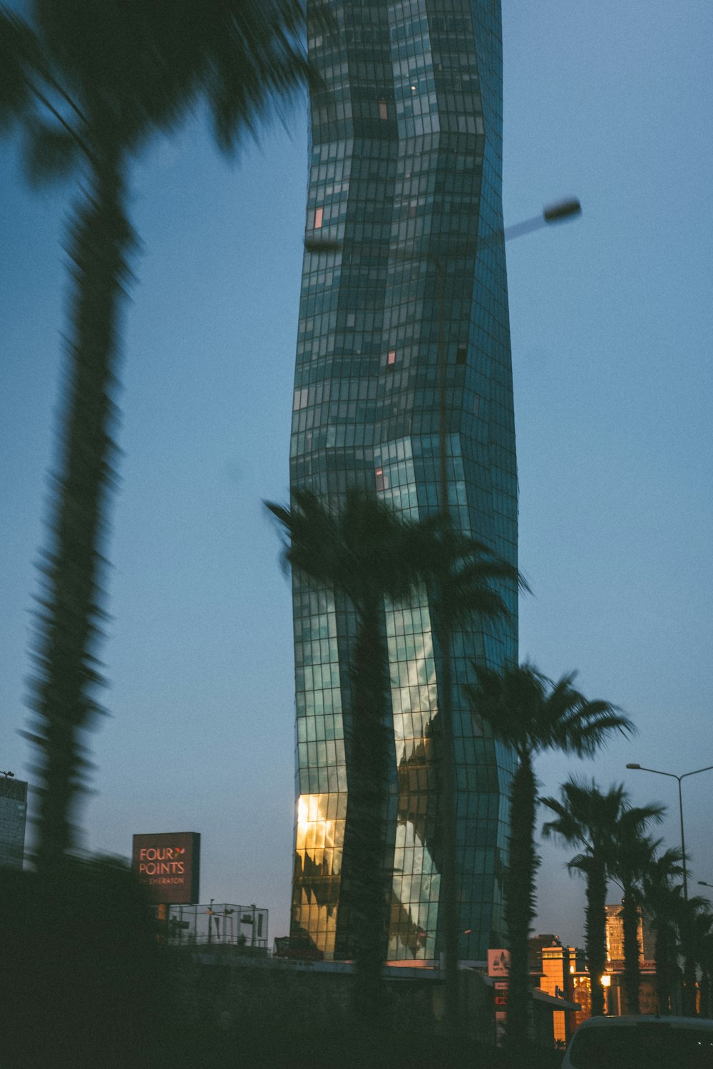 a tall building with a lot of windows next to palm trees