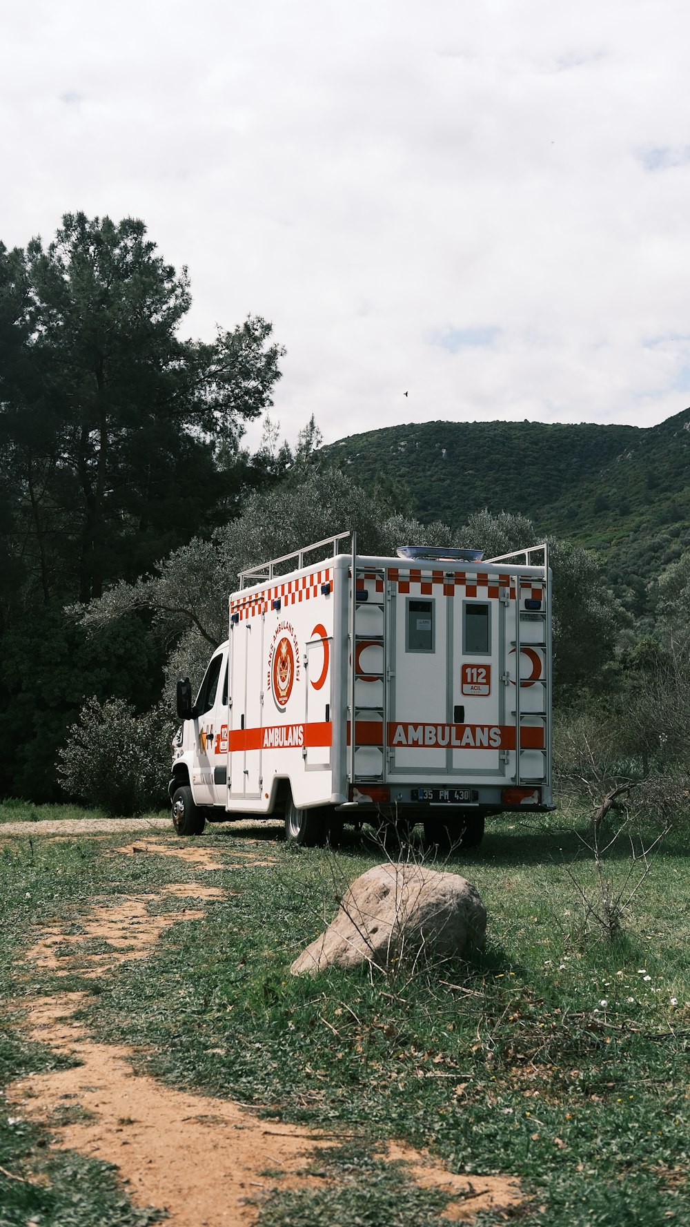 an ambulance parked on the side of a dirt road