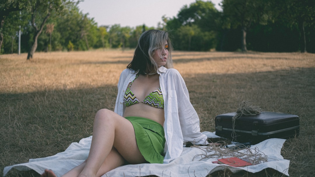 a woman sitting on a blanket in a field, A beautiful girl at picnic