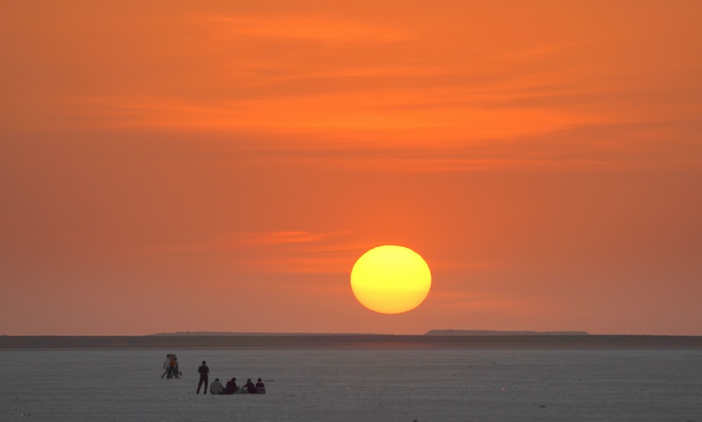 a group of people standing on top of a sandy beach