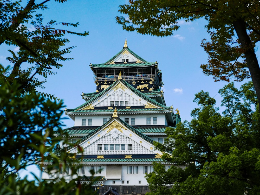 a tall white and green building surrounded by trees