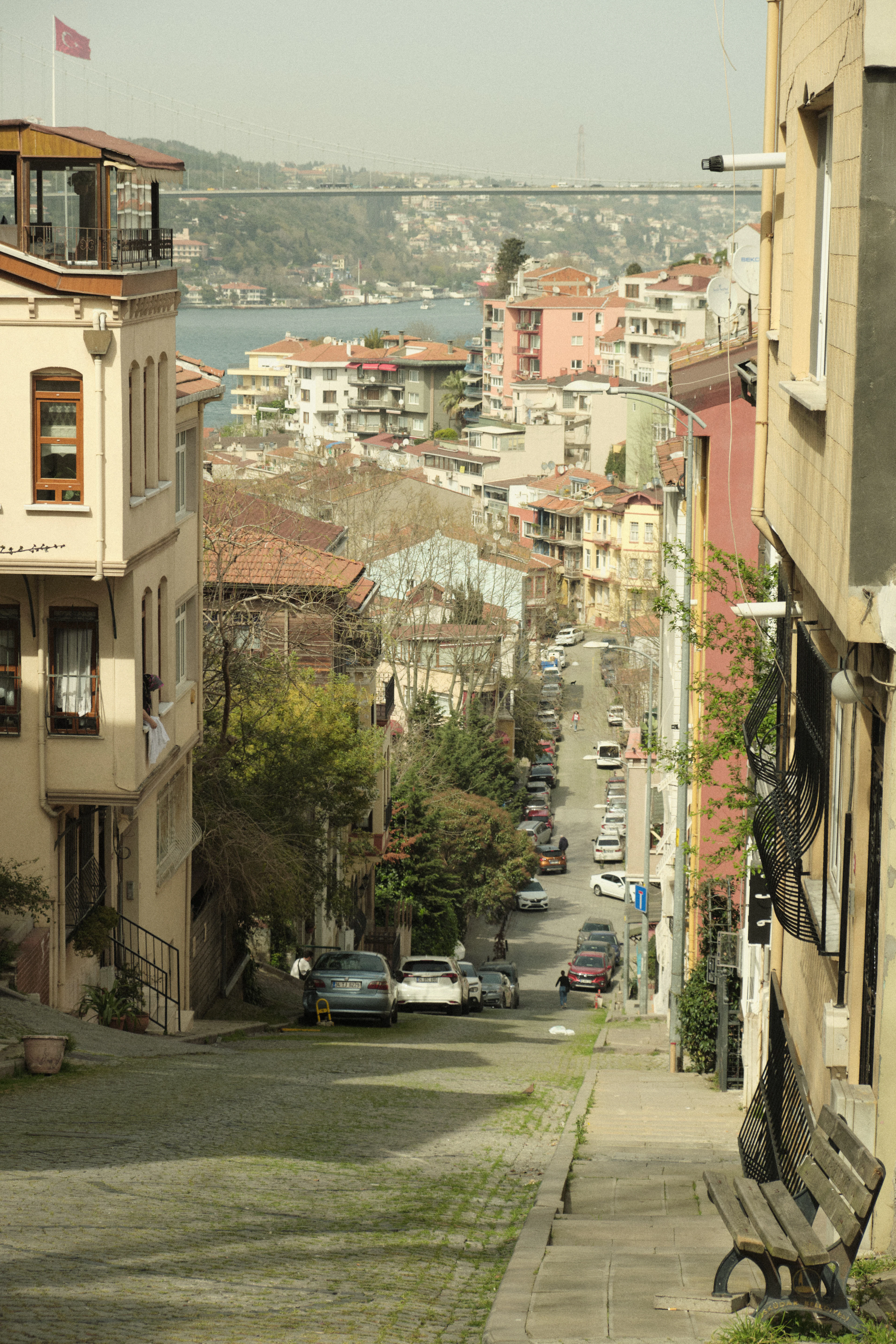 A steep street of old houses in Kuzguncuk running down towards the Bosphorus and a bridge beyond