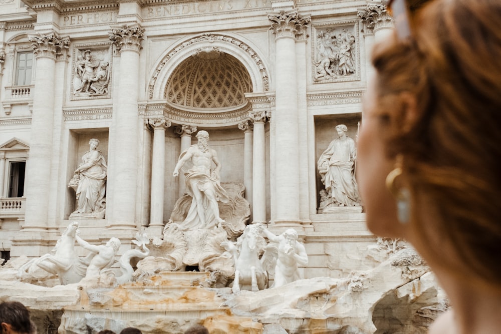 a woman looking at a statue in front of a building