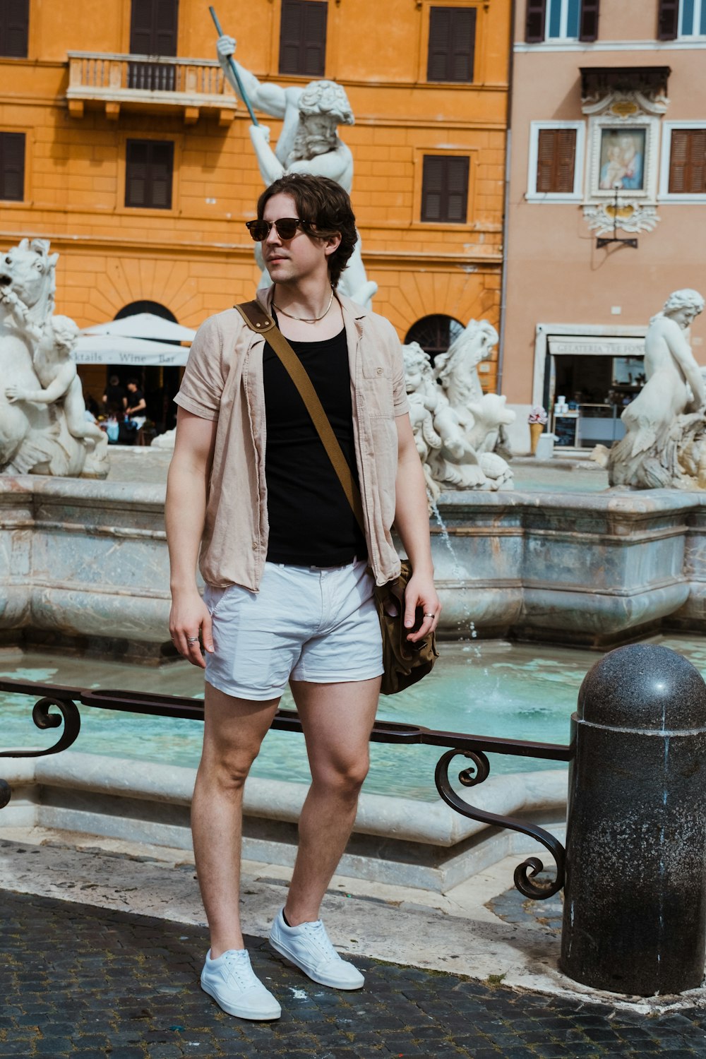 a man standing in front of a fountain in a city