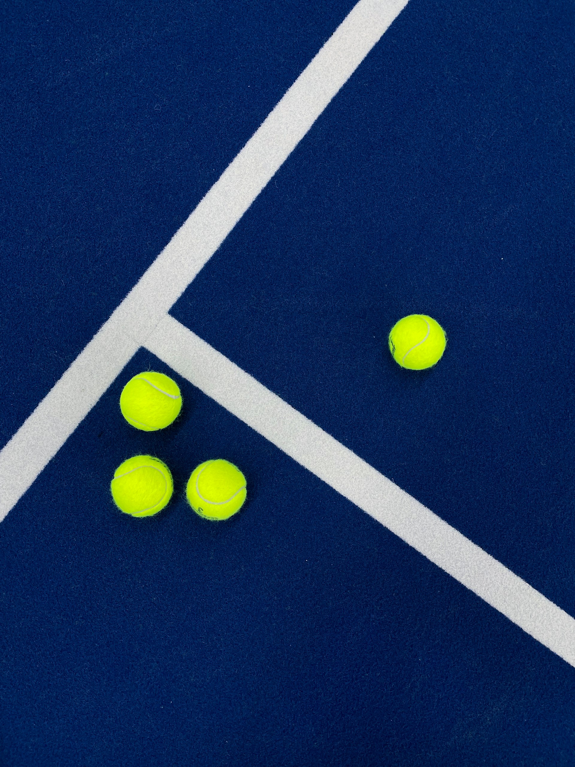 three tennis balls on a blue court with white lines