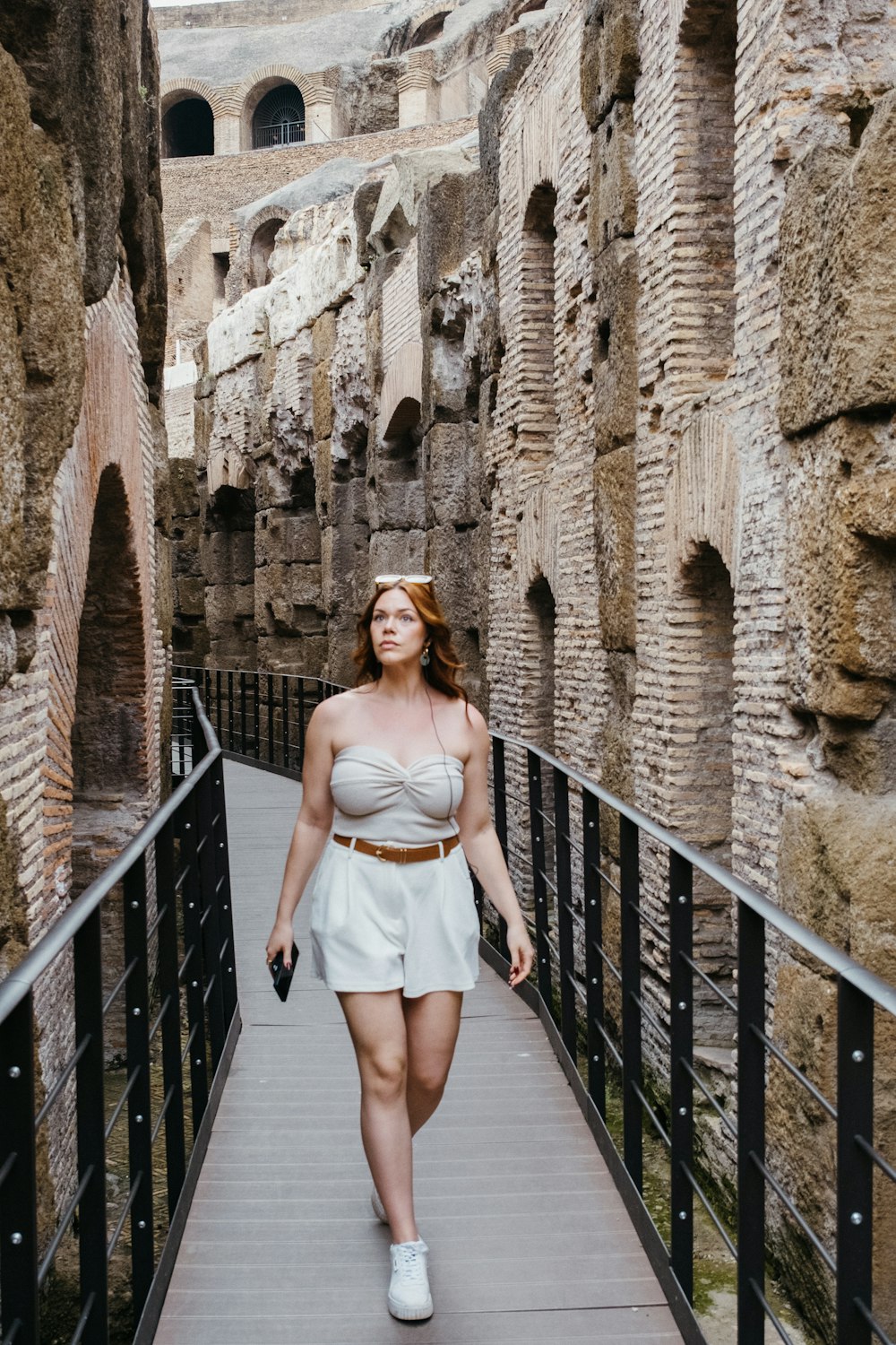 a woman in a white dress walking down a walkway