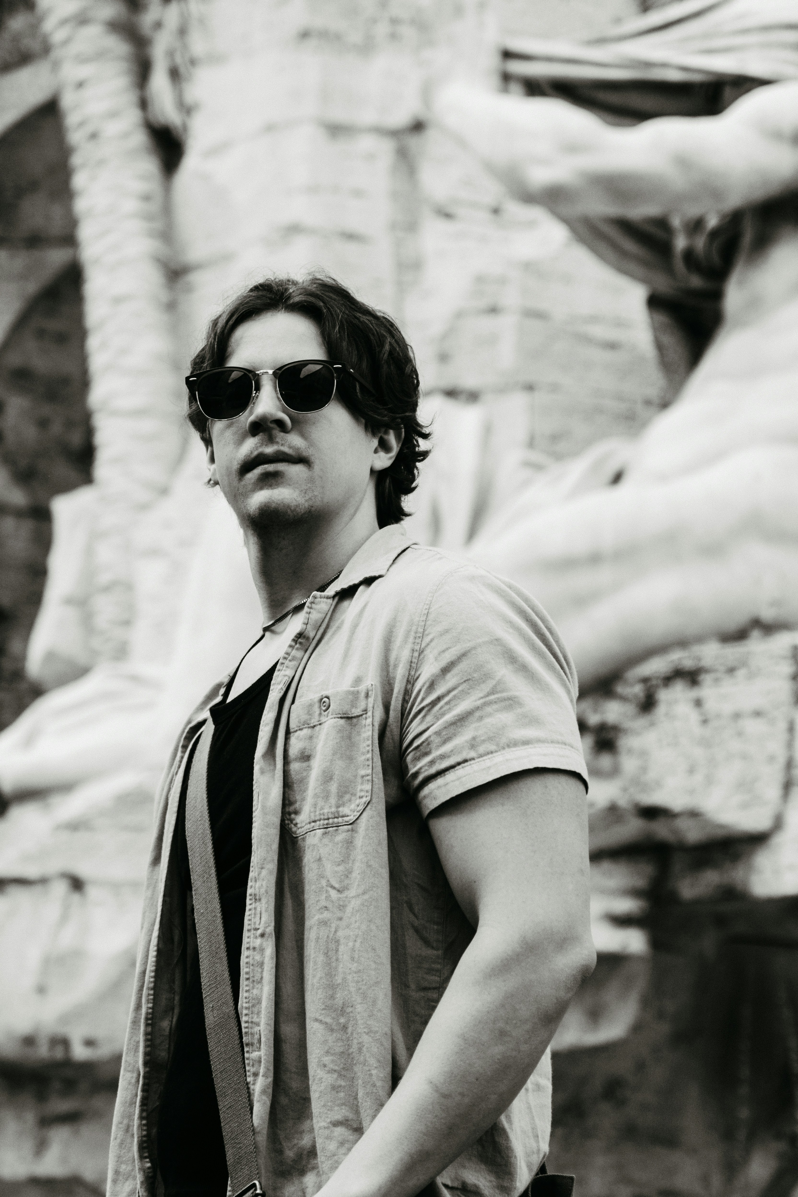 Ein Mann mit Sonnenbrille steht vor einer Statue