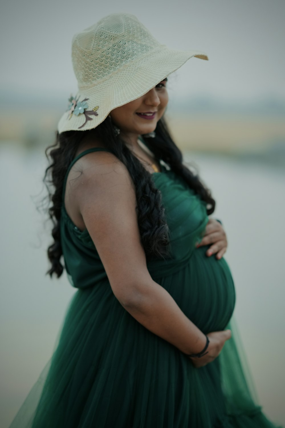 a pregnant woman wearing a green dress and a hat