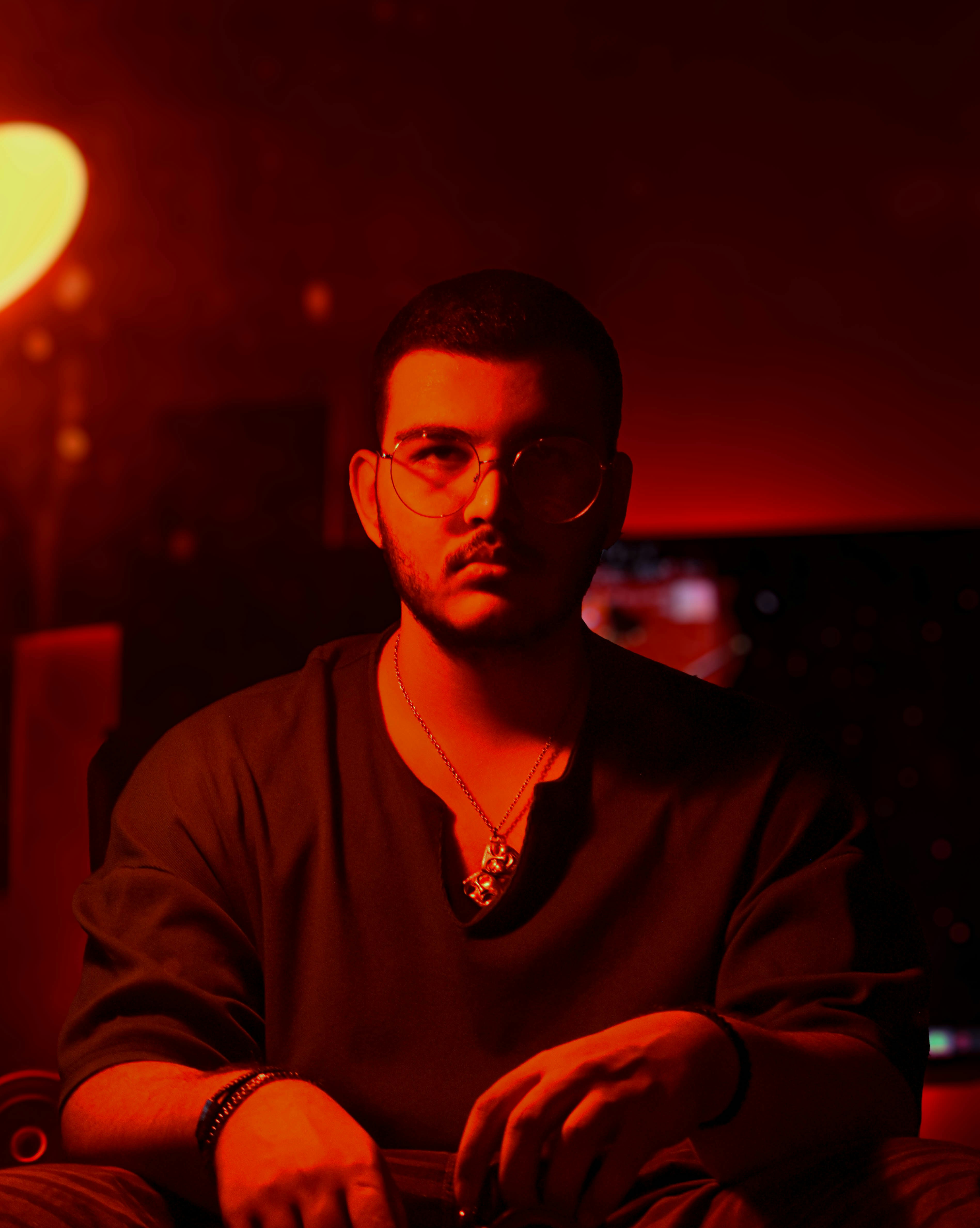 a man with glasses sitting in a dark room