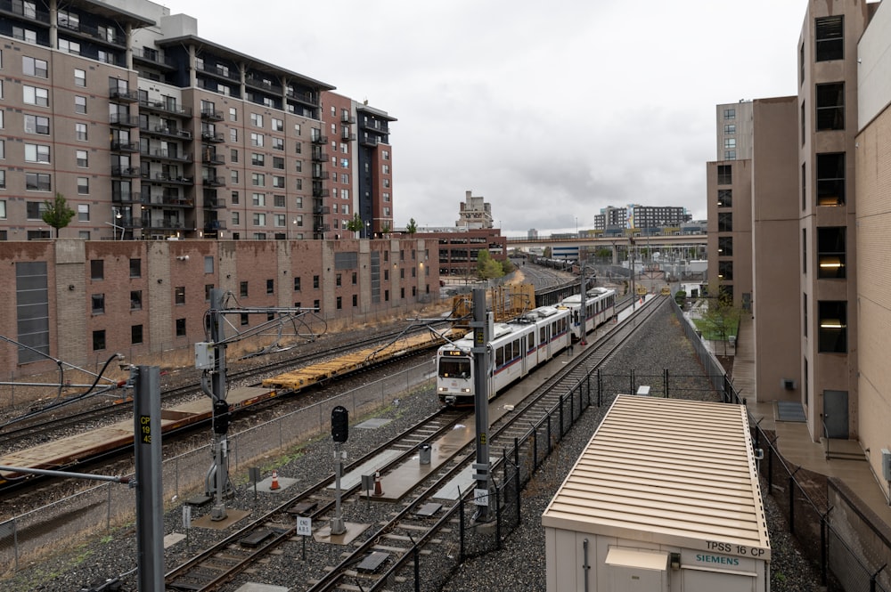 a train traveling down train tracks next to tall buildings