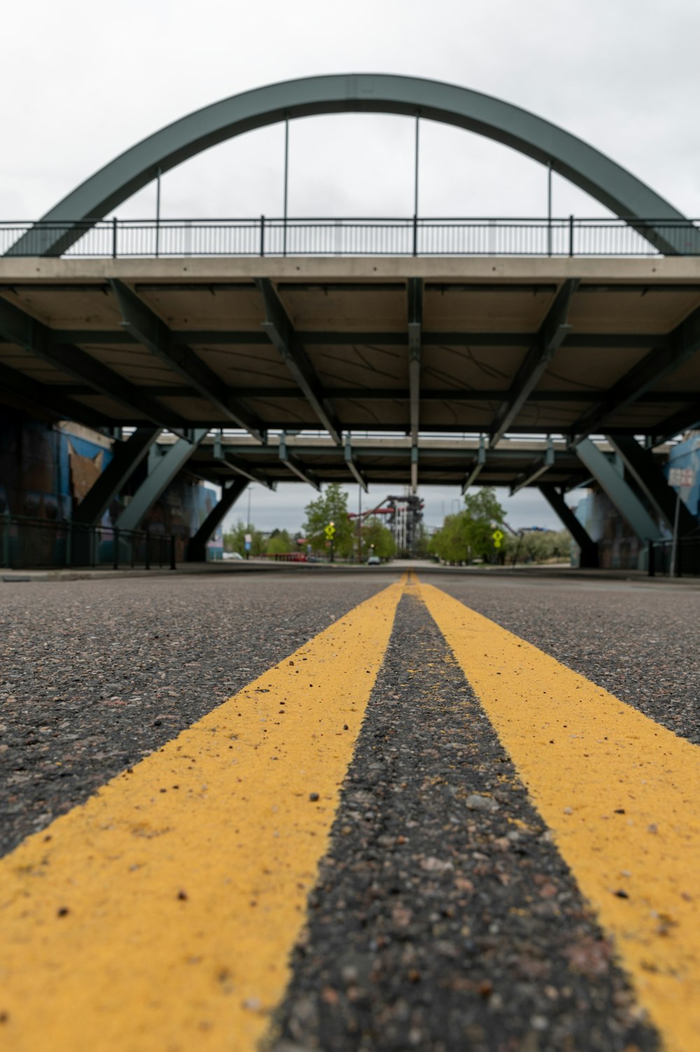 a yellow line on the road under a bridge