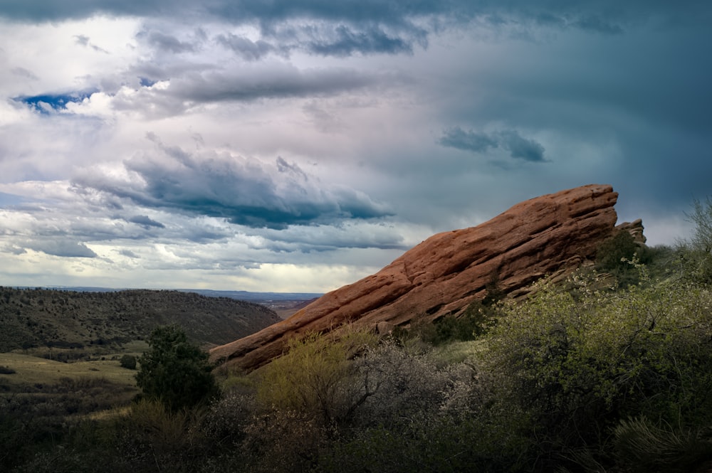 a large rock sitting on top of a lush green hillside