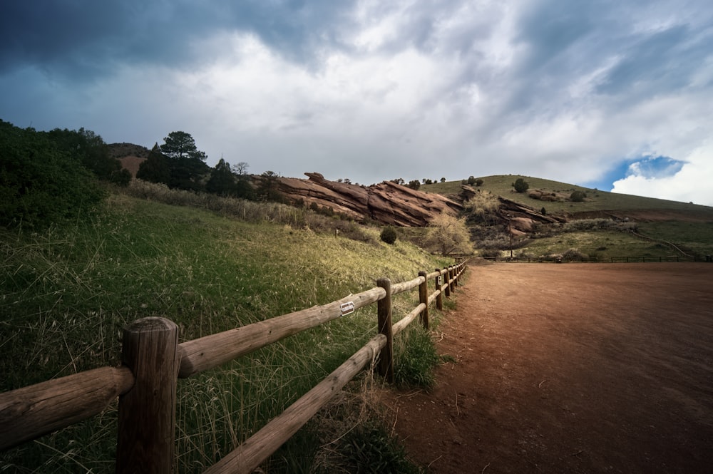 a dirt road with a wooden fence on the side of it