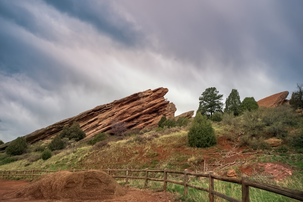 a wooden fence in front of a large rock formation