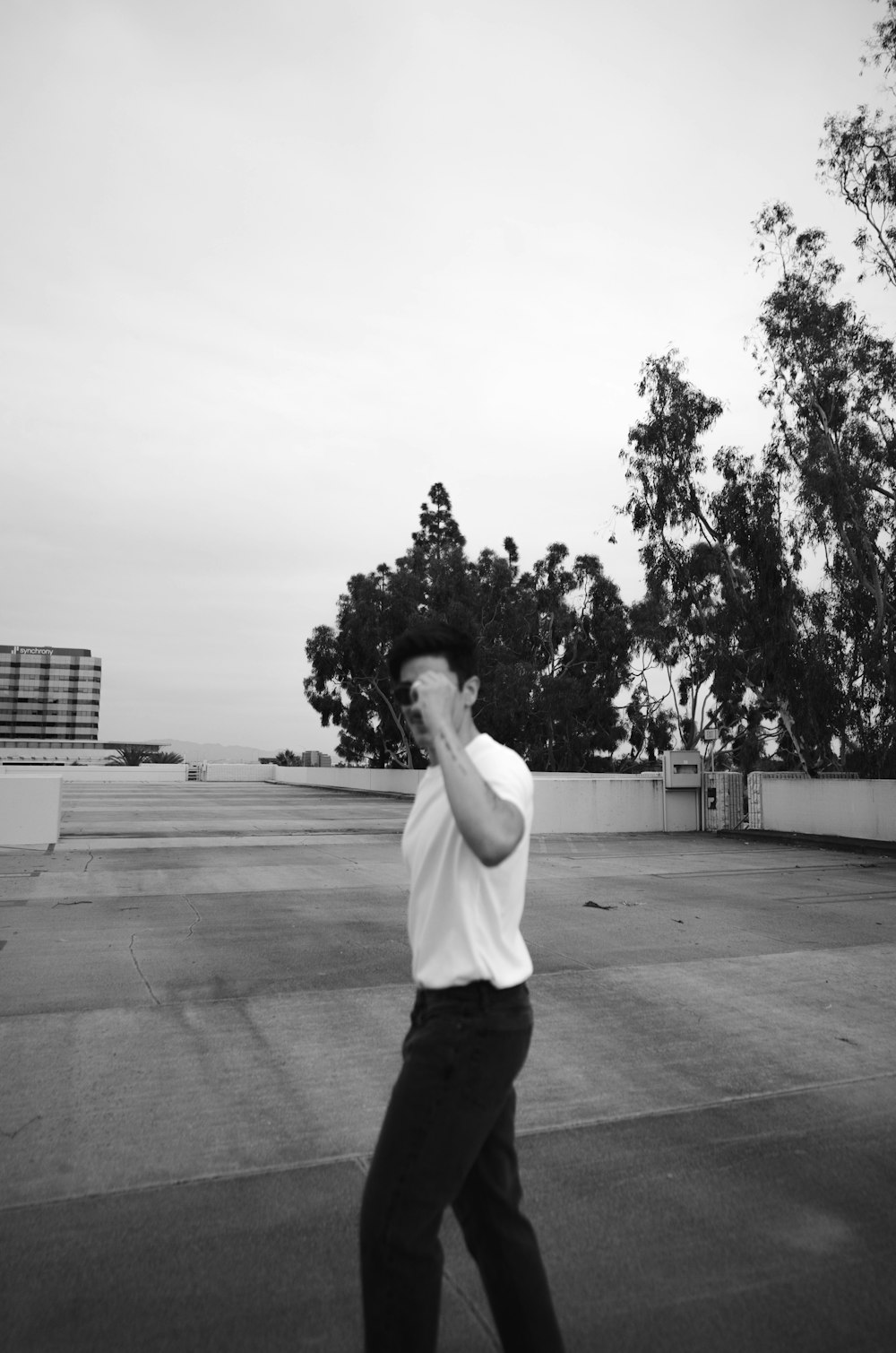 a man walking across a parking lot while talking on a cell phone